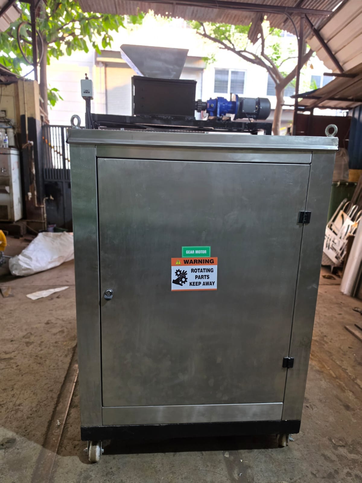 Side profile of the UAE composter highlighting gear motor drive, warning signage, and crane eye-bolts